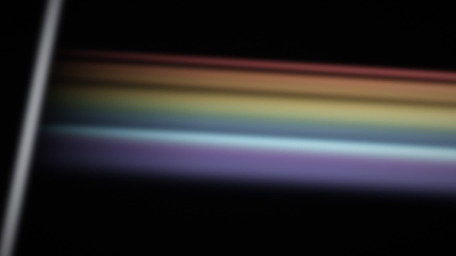 A single lit edge of glass casting an ordered spectral fan into darkness.