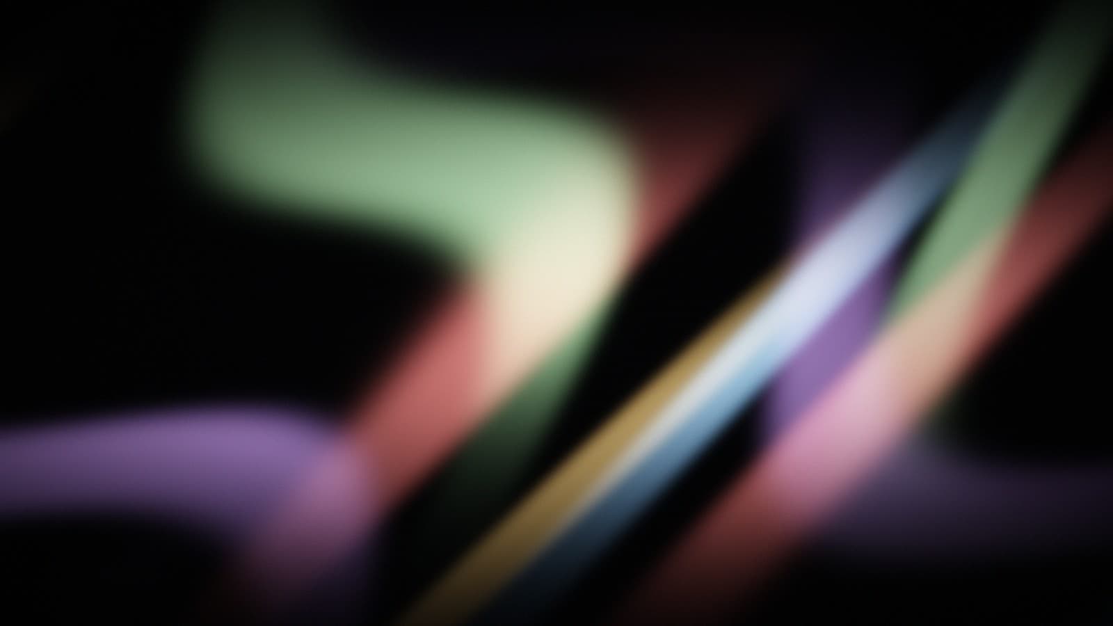 Soft ribbons of refracted colour folding over one another against black.