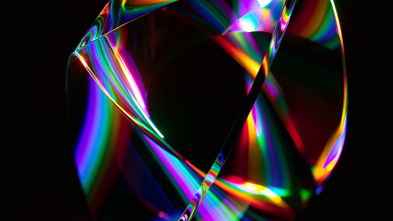 A faceted glass solid in darkness, splitting light into full spectrum bands.